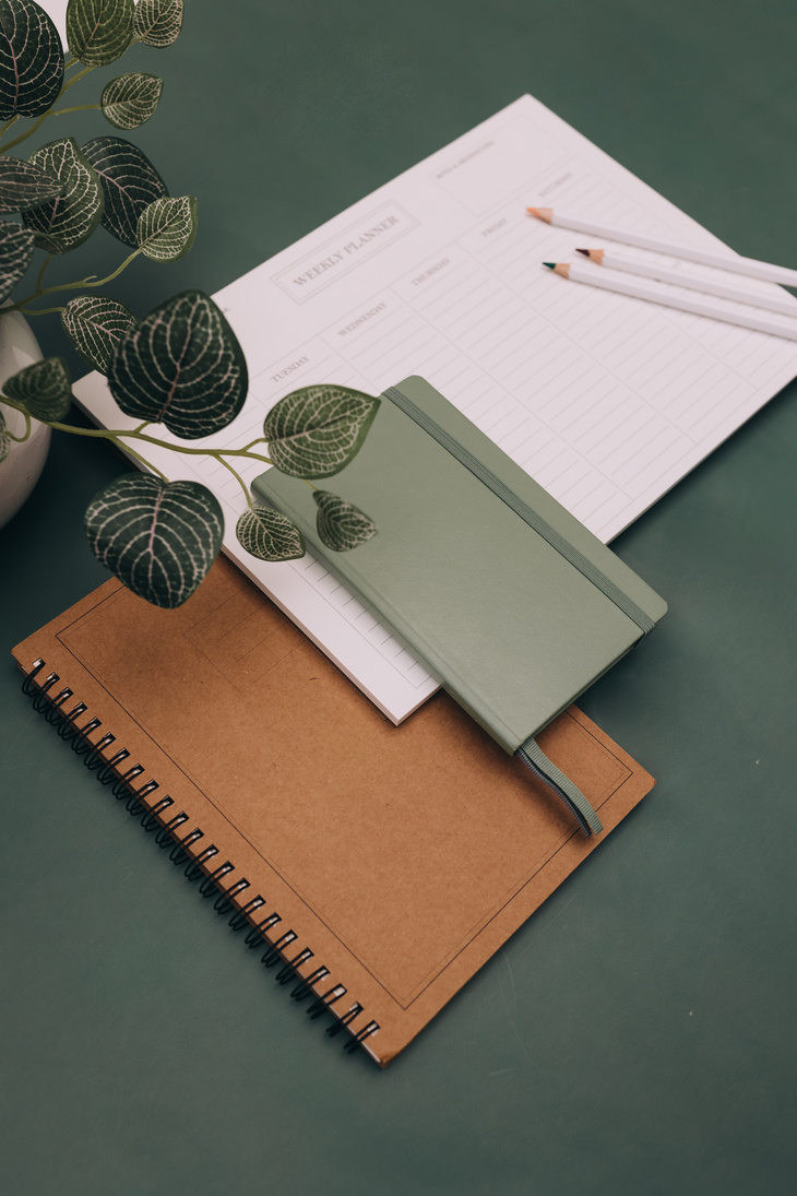 Notebooks, Calendar and Pencils on Green Background